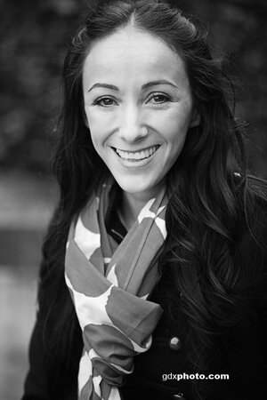 A black and white picture of a Latina woman with long dark hair. She's wearing a light scarf and a black jacket